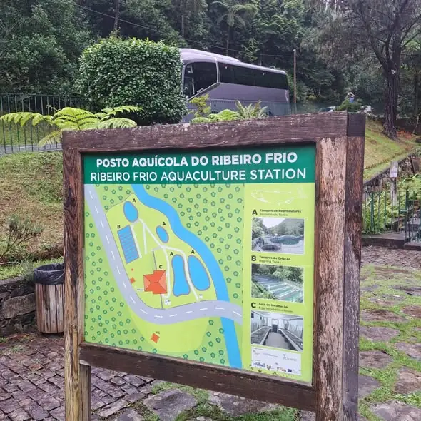 Painel do posto aquícola do Ribeiro Frio, com o autocarro do grupo ao fundo